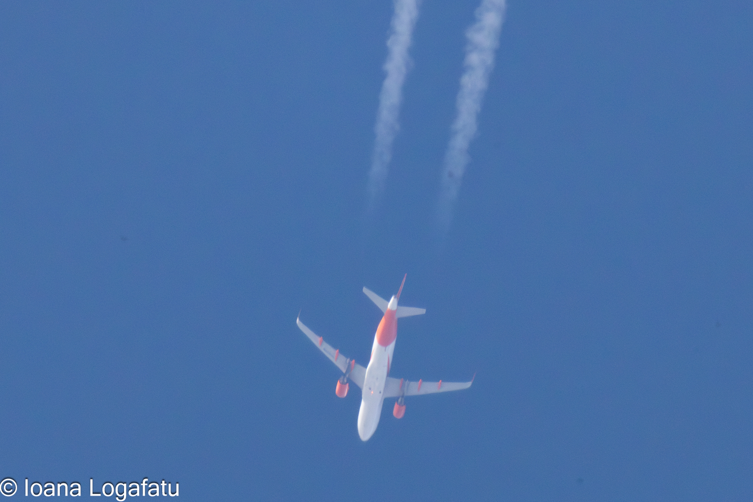 Jet soaring high with contrails